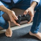 Hands of barefoot man playing computer game at home, close-up