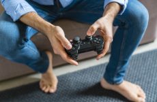 Hands of barefoot man playing computer game at home, close-up