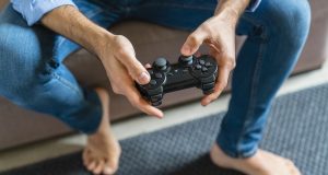 Hands of barefoot man playing computer game at home, close-up